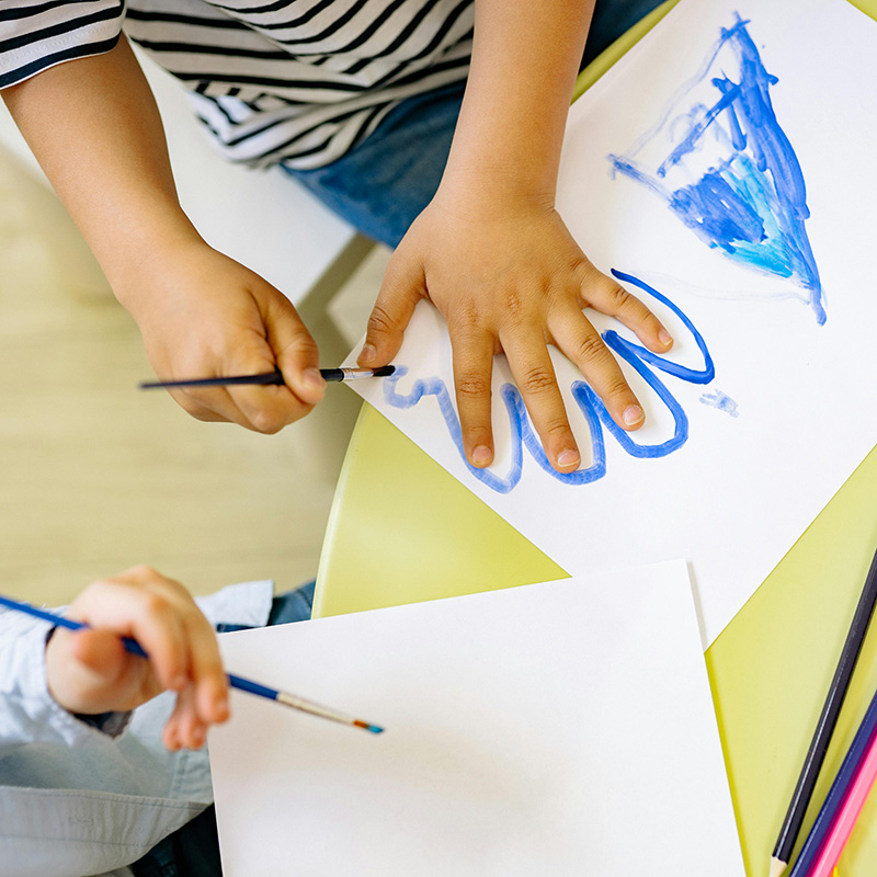 Child tracing his hand in paint; Early Childhood Developmental Evaluations